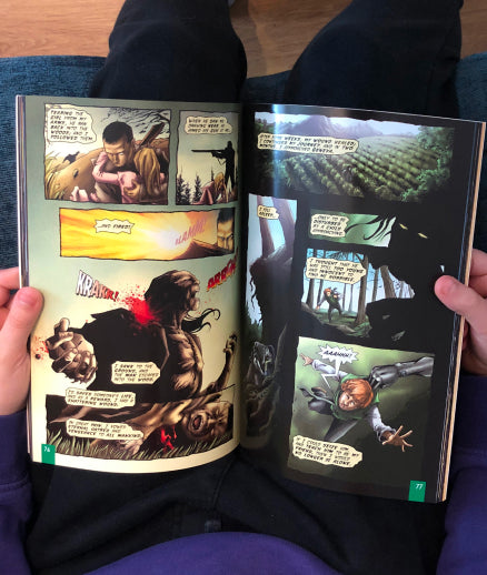 A young boy reads an open copy of Frankenstein The Graphic Novel, Quick Text, on his lap.